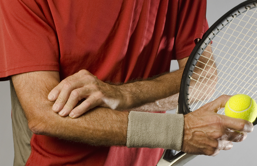 Man rubbing elbow after playing tennis