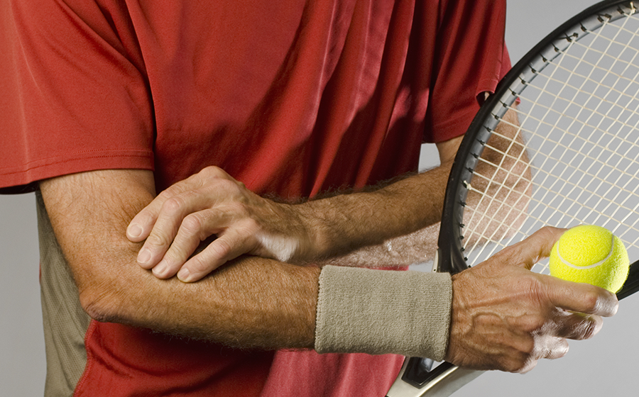 Man rubbing elbow after playing tennis