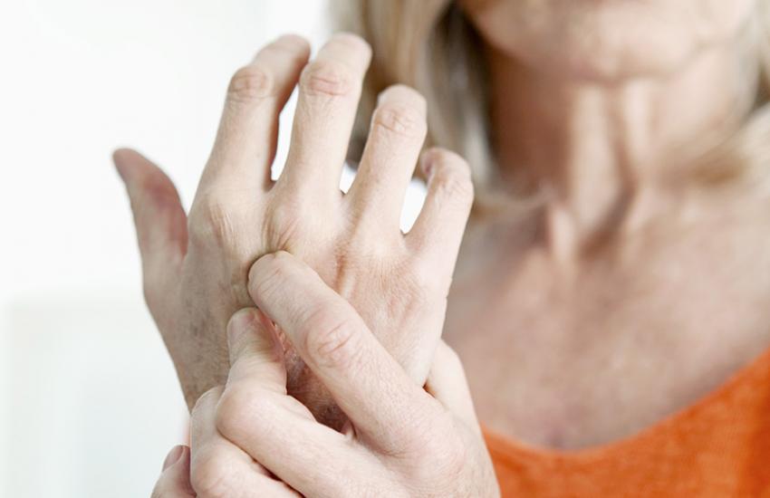 woman holding arthritic hand in pain