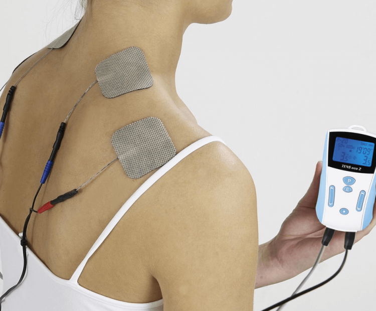 Woman using TENS unit on shoulders