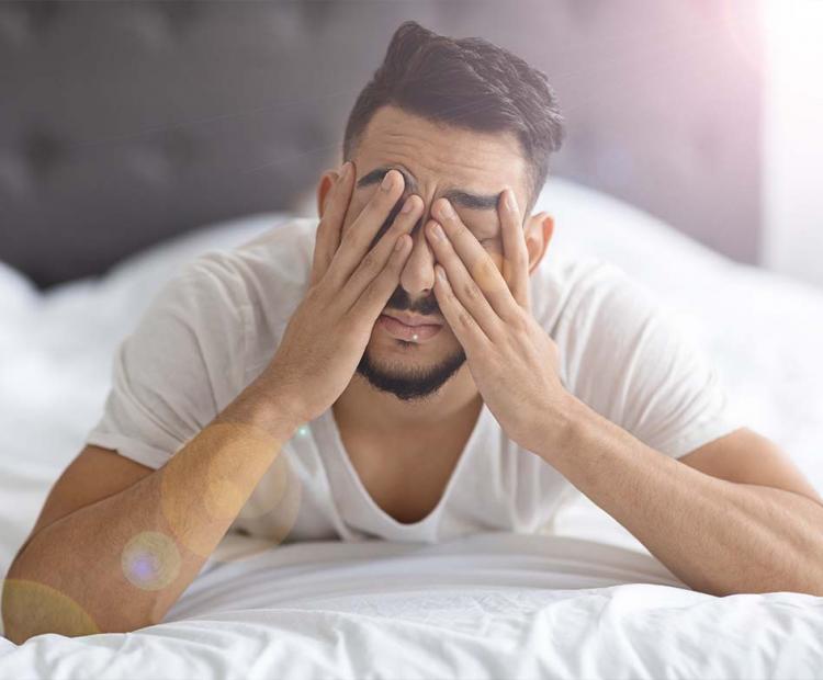 Man with migraine closing eyes to block out light