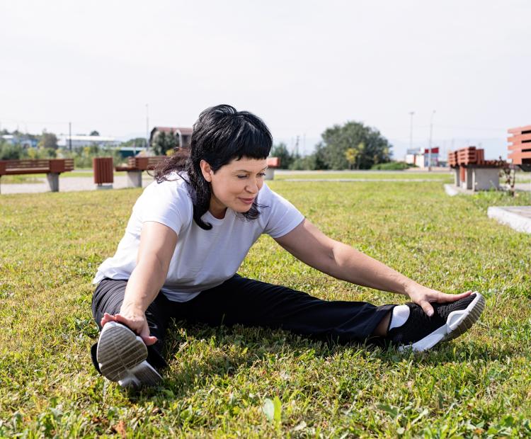 Woman sitting on grass stretching.