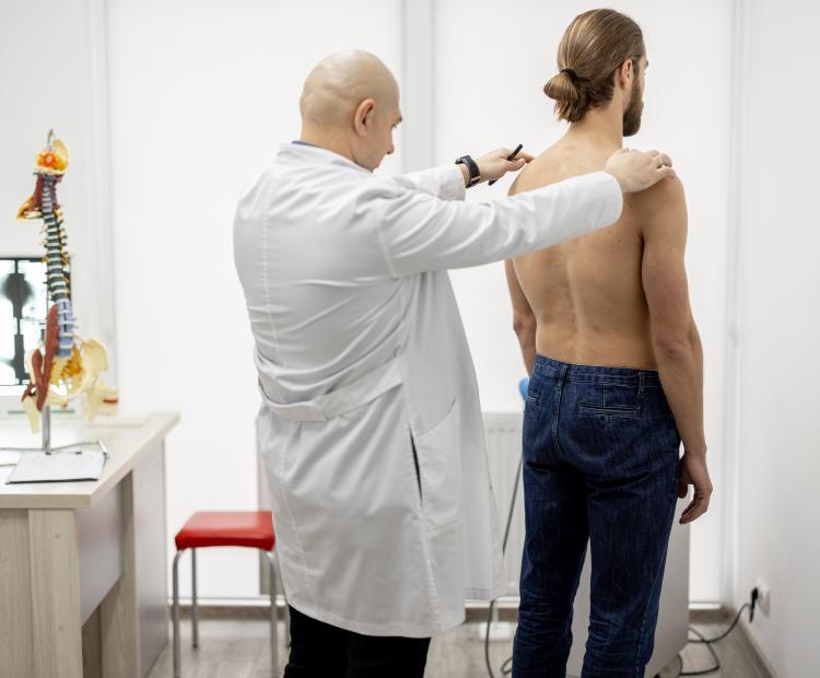 A doctor examining a patient's back for back pain causes. 