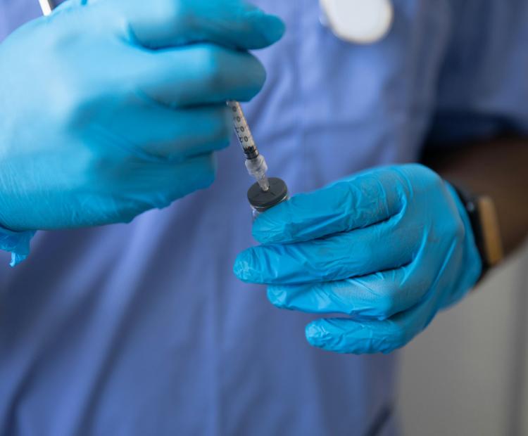 Image of a healthcare professional preparing a syringe before injection.