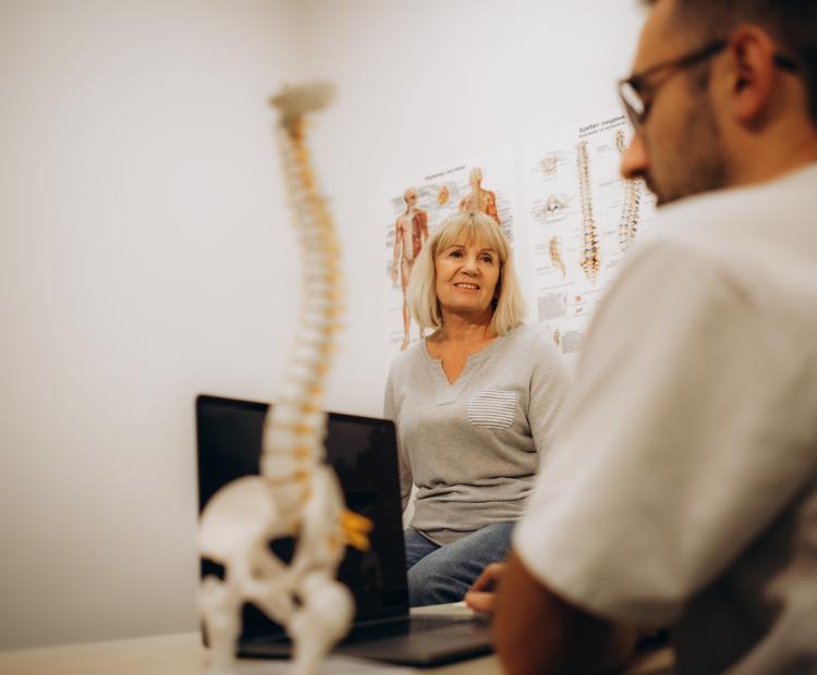 A healthcare professional describing spine treatments for scoliosis to an elderly patient.
