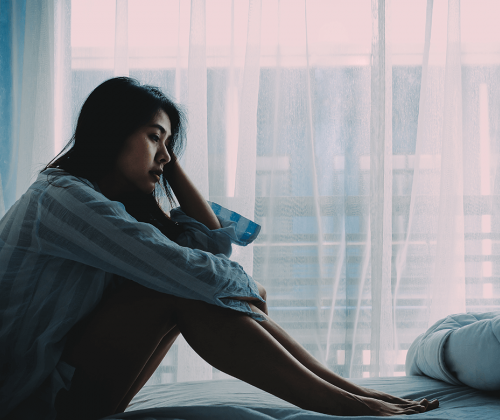 Woman sitting on bed in pain