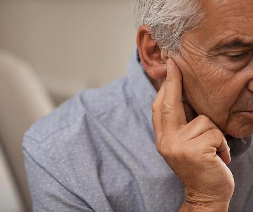 Senior man touching side of face