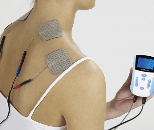 Woman using TENS unit on shoulders