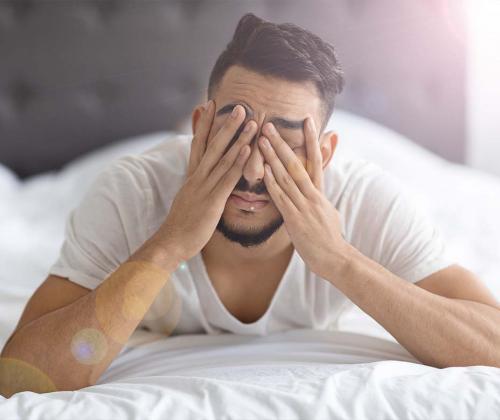 Man with migraine closing eyes to block out light