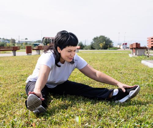 Woman sitting on grass stretching.