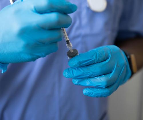 Image of a healthcare professional preparing a syringe before injection.