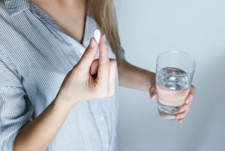 Woman taking ibuprofen pill