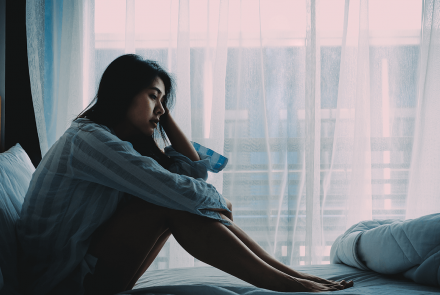 Woman sitting on bed in pain