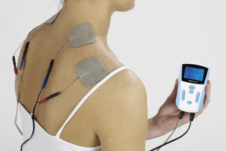 Woman using TENS unit on shoulders