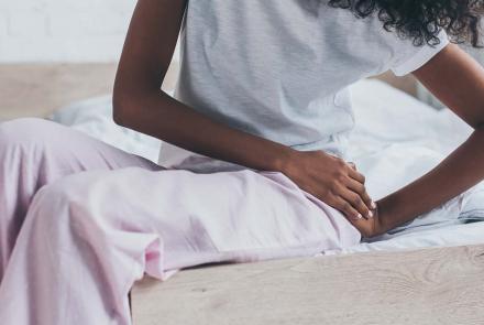 Woman sitting on bed with hip pain